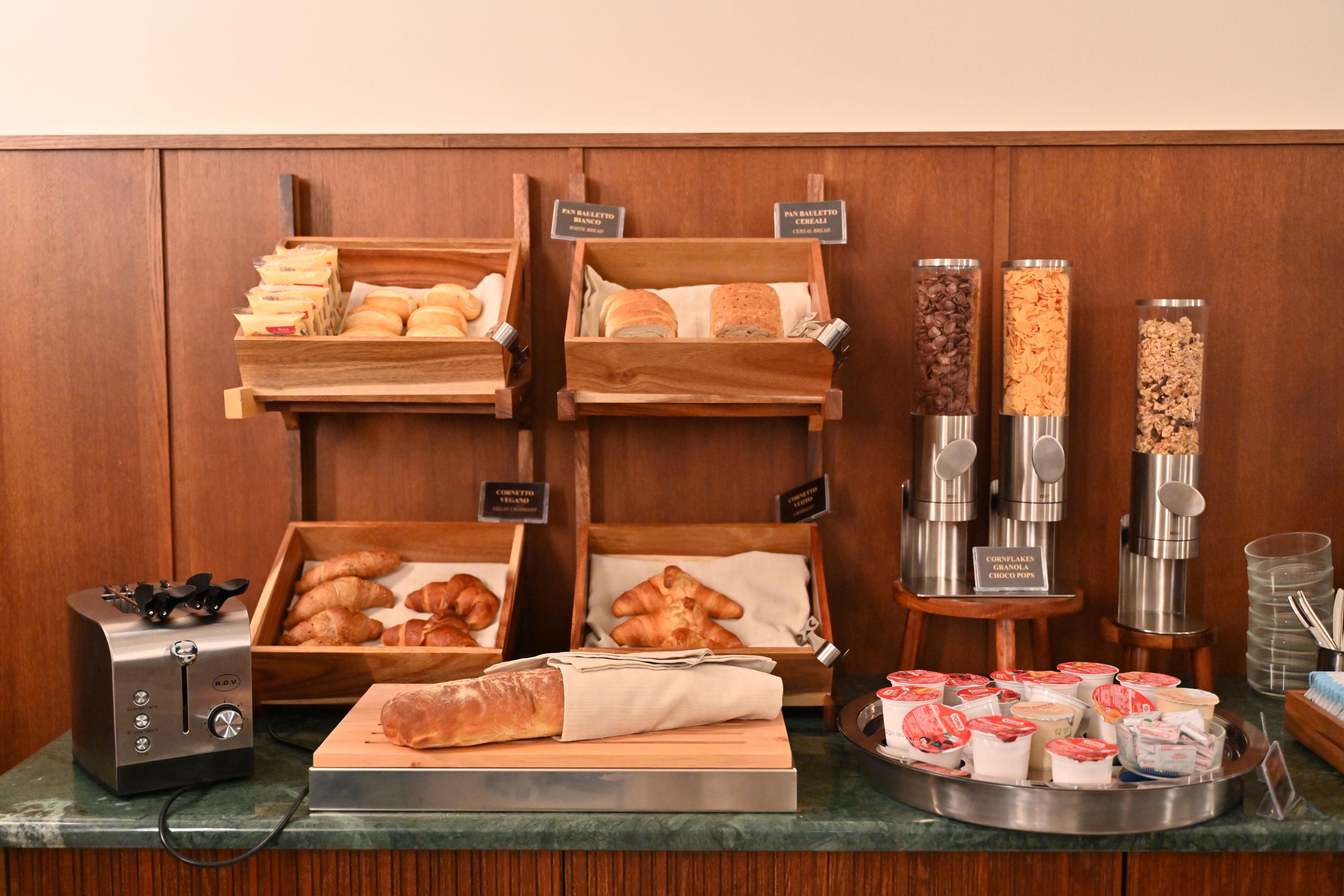 Un buffet della colazione con diversi tipi di pane, pasticceria e una macchina del caffè.