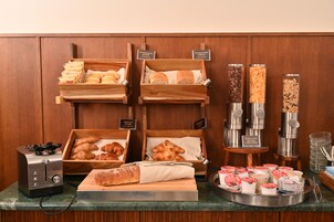 Un buffet della colazione con diversi tipi di pane, pasticceria e una macchina del caffè.