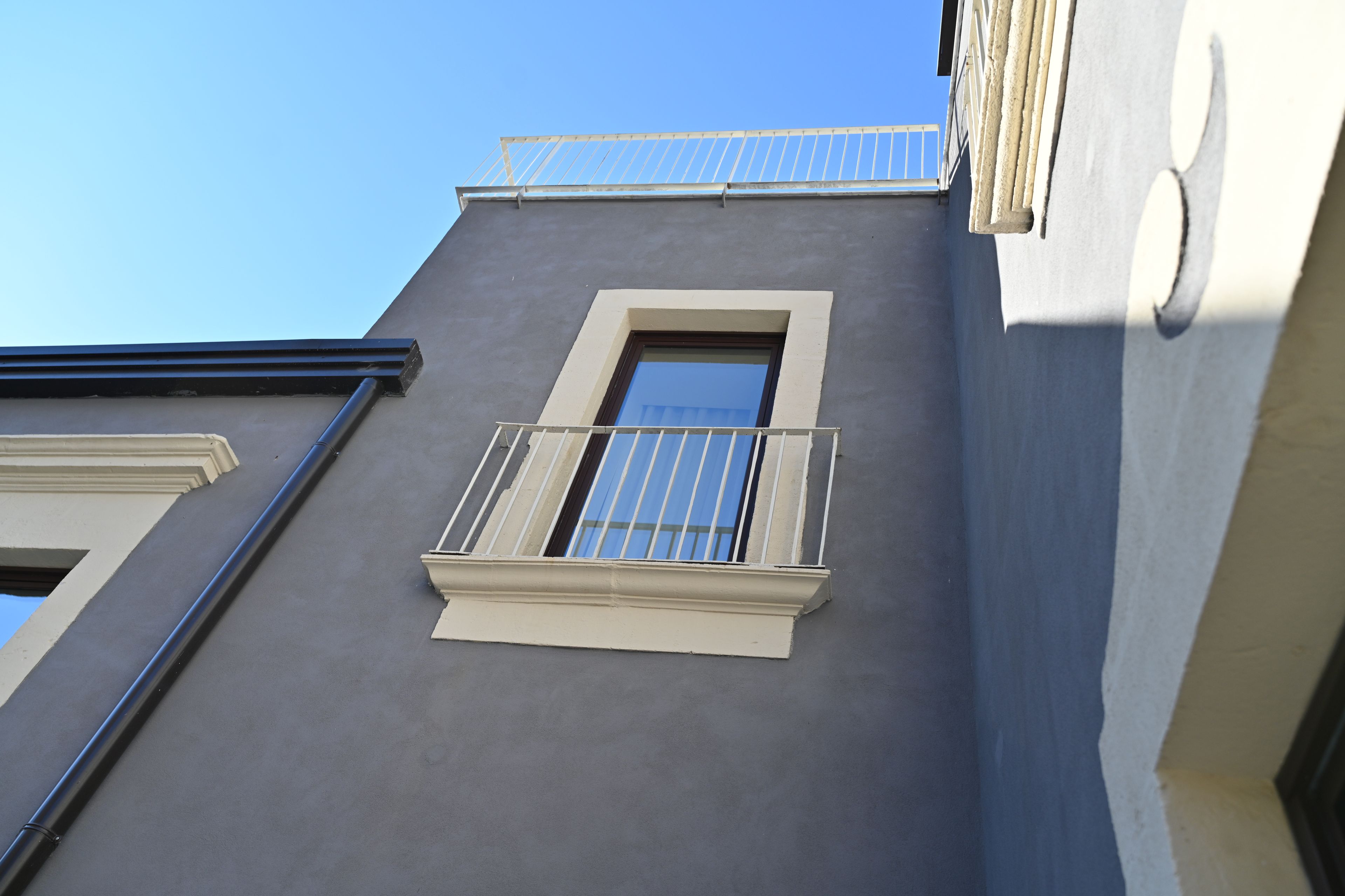 A building facade with a window and a balcony.