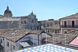 Vista de un edificio histórico con una cúpula y un campanario, rodeado de tejados de tejas rojas.