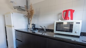A modern kitchen with a white refrigerator, a microwave, and a red kettle on the counter. - Apartur Buenos Aires (Buenos Aires)