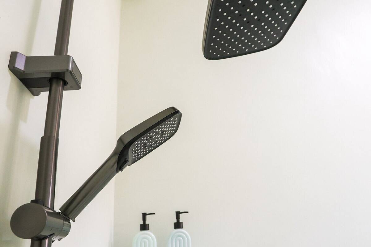 A shower with a handheld showerhead and a fixed overhead showerhead mounted on a wall.