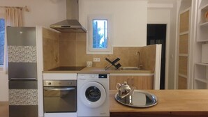 Een kleine keuken met een wasmachine, oven en een raam boven de spoelbak.