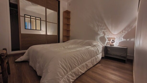 Een slaapkamer met een bed, nachtkastje, spiegel en kledingkast.