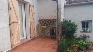 Een binnenplaats met een houten deur, een latten hekwerk en potplanten.