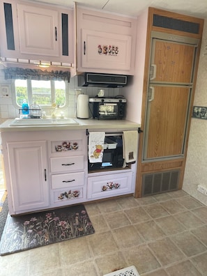 Una cocina compacta con horno empotrado, microondas y refrigerador.