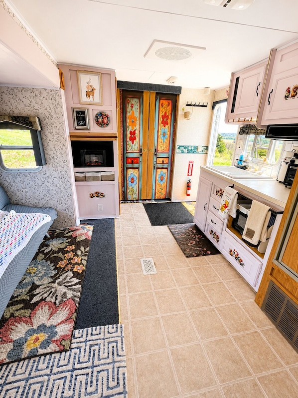 A compact RV kitchen with a microwave, sink, and stove.