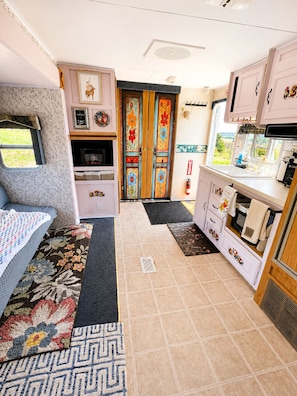 Une cuisine compacte pour camping-car, Ă©quipĂ©e dâun four Ă micro-ondes, dâun Ă©vier et dâune cuisiniĂšre.