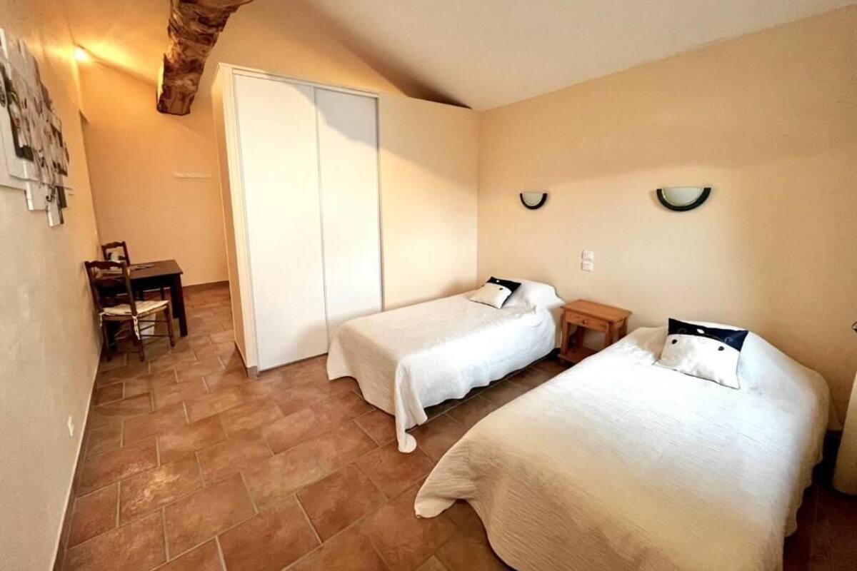 A room with two beds, a wooden chair, a desk, and a wardrobe.