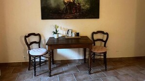 A dining area with a table and two chairs, a painting above the table, and a potted plant on the table. - Les étoiles (Mareugheol)