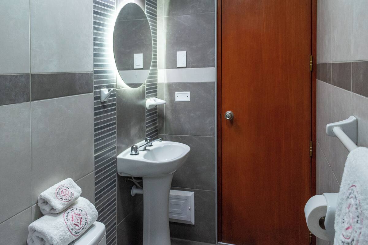 A bathroom with a sink, mirror, towel rack, and a wooden door.
