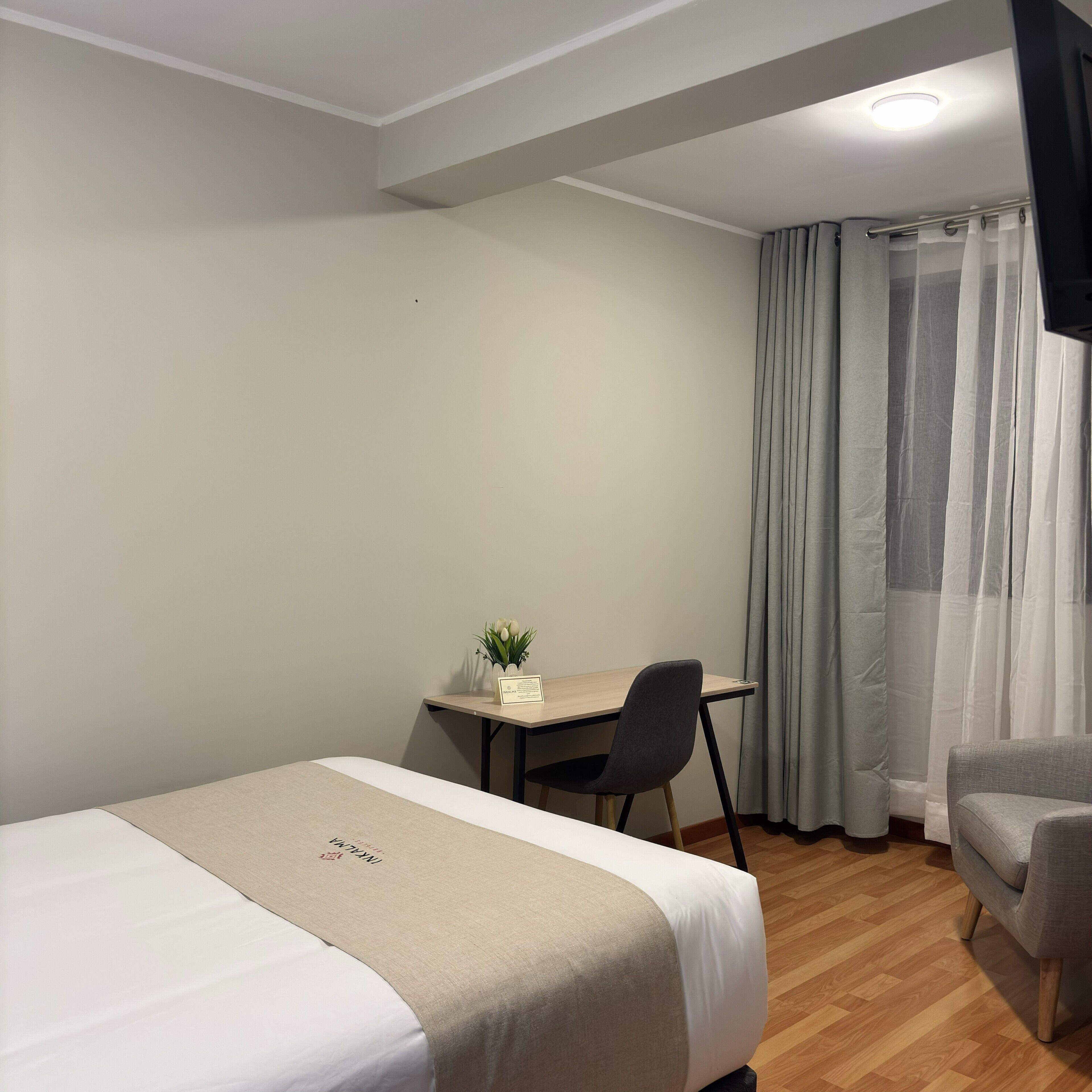 A hotel room with a bed, a desk, a chair, and a TV.