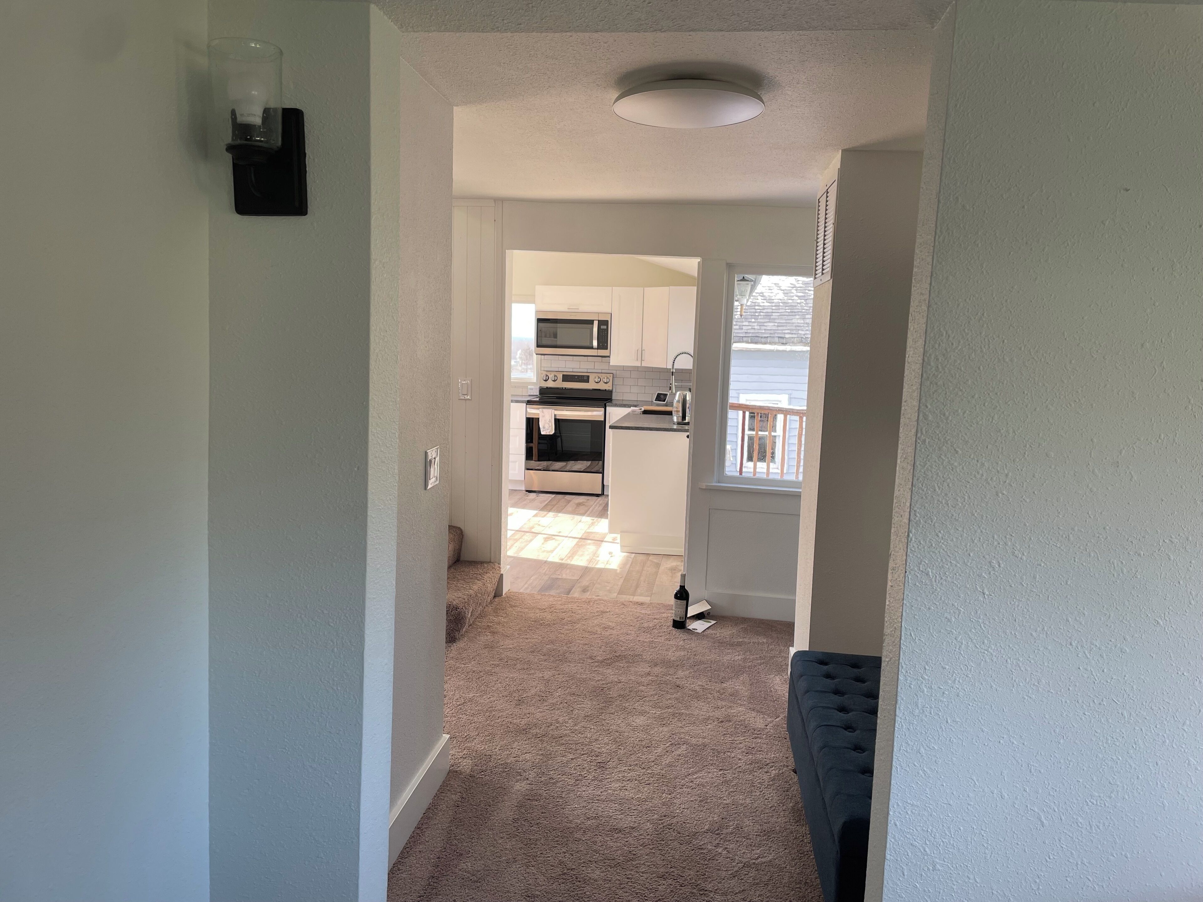 A hallway leading to a kitchen with a microwave, oven, and a small island.