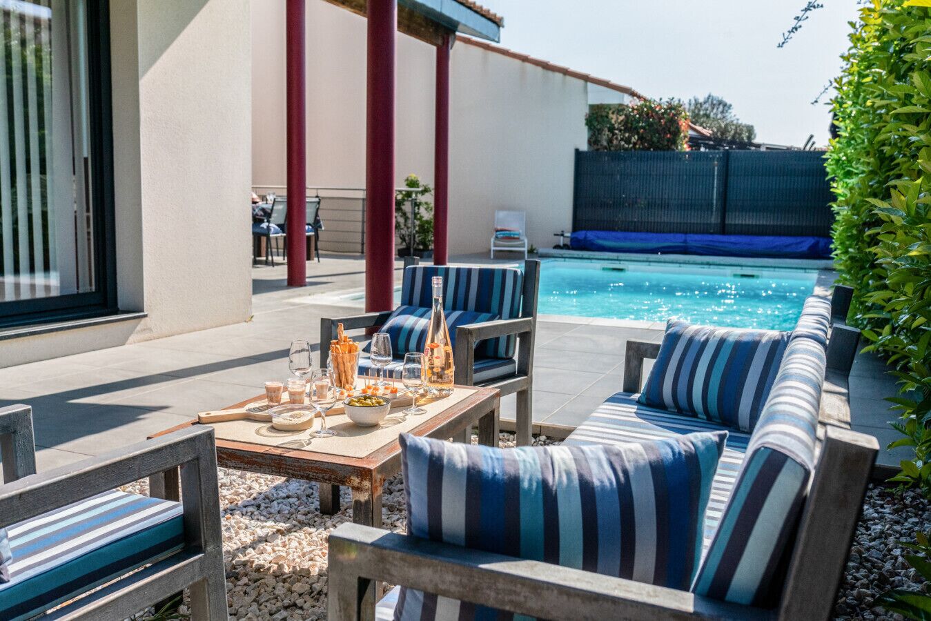 An outdoor seating area with a pool, wooden furniture, and a clear view of the pool.