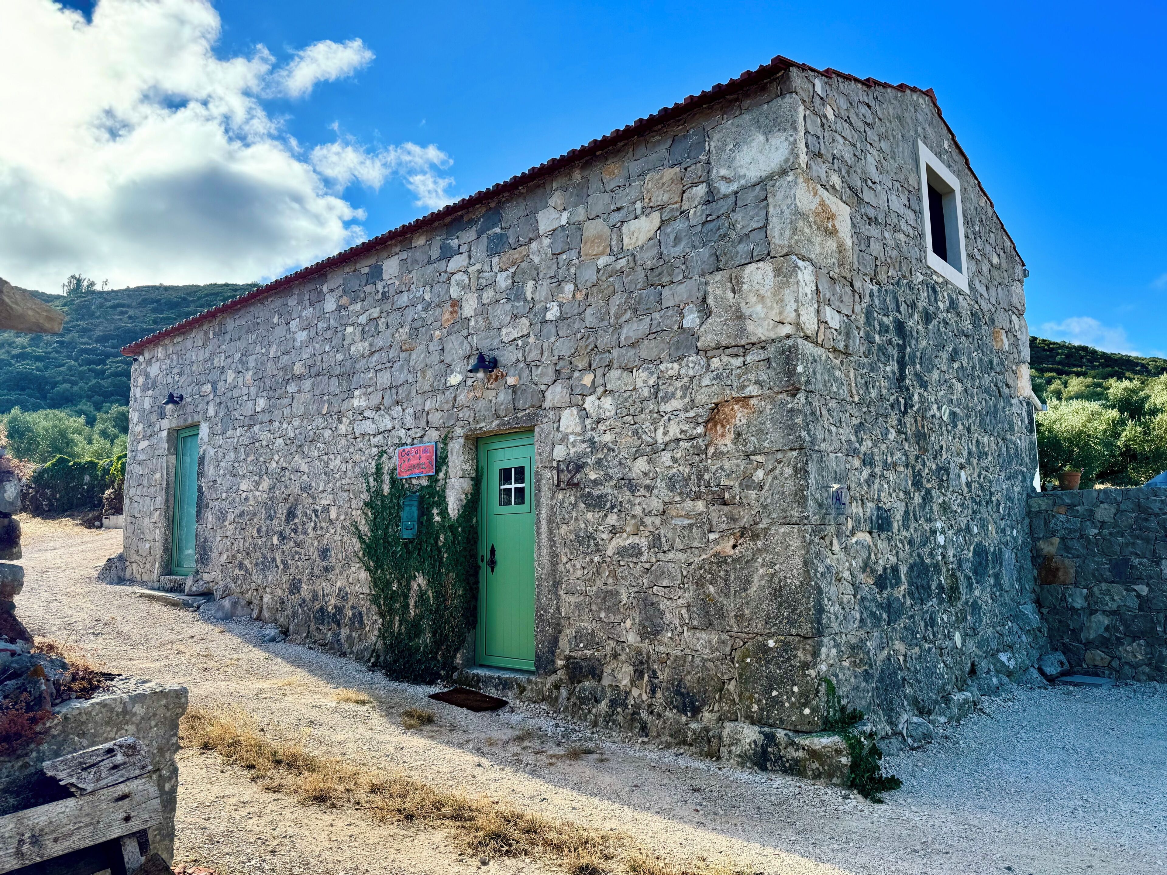 A stone building with a green door, a small window, and a sign on the wall.