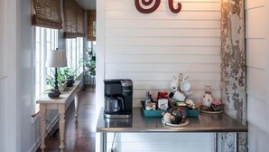 Una cocina con una cafetera Keurig, una bandeja azul verdoso con varios objetos, y una gran letra decorativa 'R' en la pared.