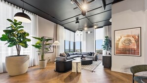 A modern living room with a sectional sofa, a coffee table, and large potted plants. - Chic Studio in the Heart of Miami 4 Guests (Miami)