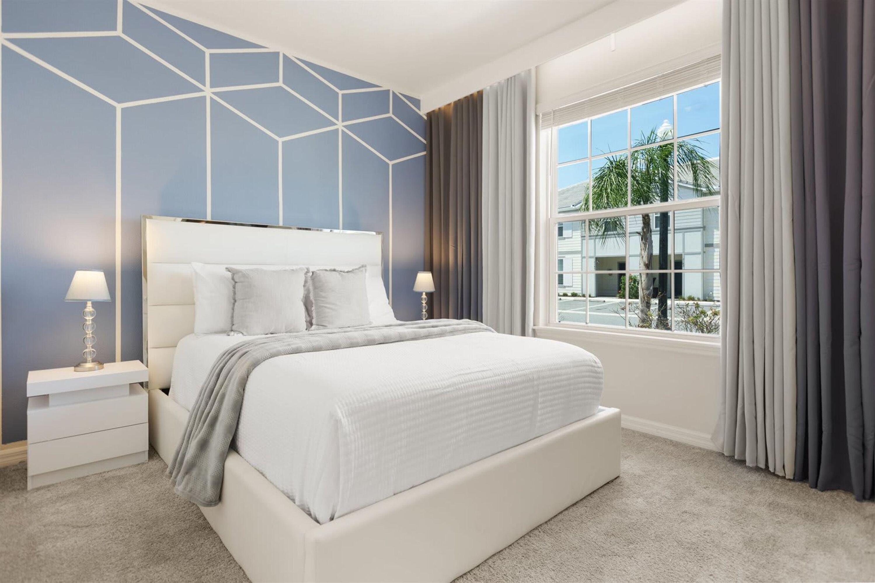 A modern bedroom with a large bed, two bedside tables, and a window with curtains.