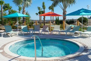 Ein Poolbereich mit Liegestühlen, Sonnenschirmen und Palmen.