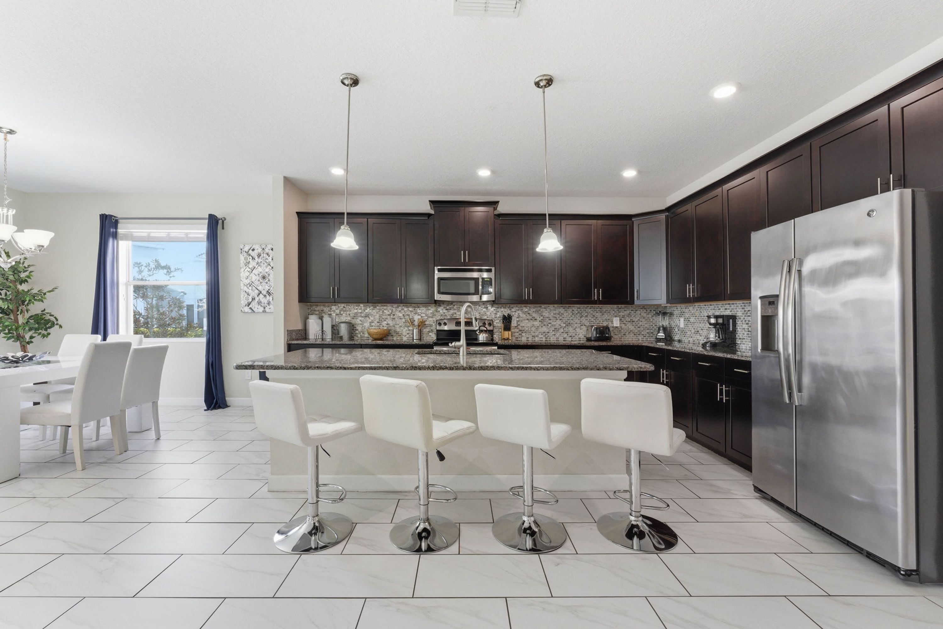 A modern kitchen with dark cabinets, stainless steel appliances, and a central island with bar stools.