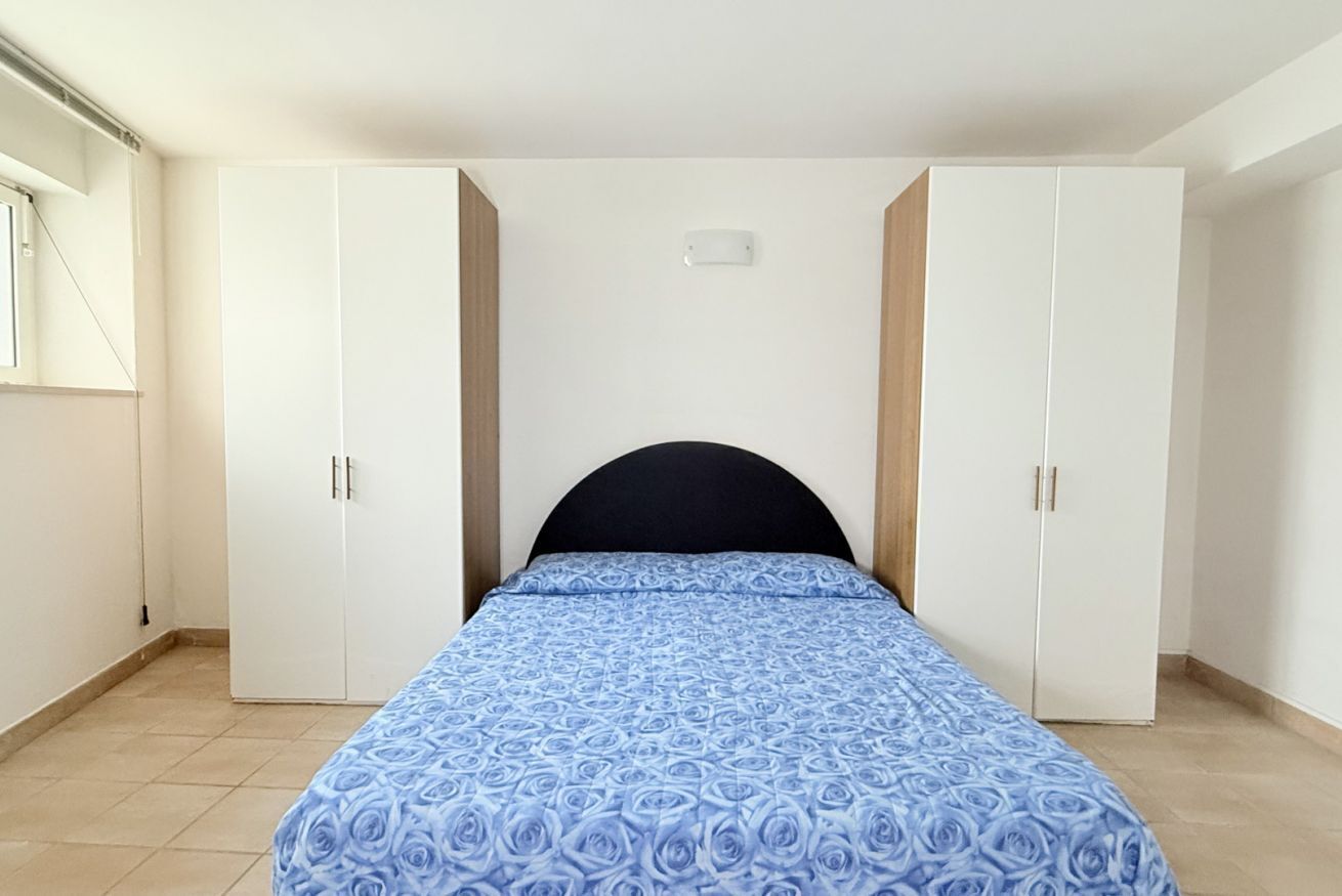 A bedroom with a bed, white wardrobes, and a window.