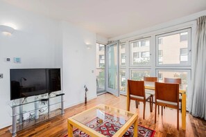 Ein modernes Wohnzimmer mit Flachbildfernseher, Glastisch und Holzsesseln.