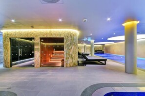 Ein moderner Wellnessbereich mit Steineingang, Pool und Lounge-Bereich.