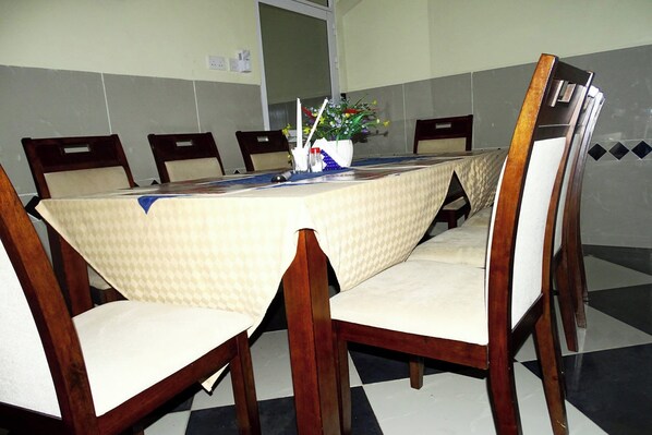 A conference room with a table covered by a patterned tablecloth, surrounded by wooden chairs with cushioned seats. - White Rhino Hotel Mombasa (Mombasa)