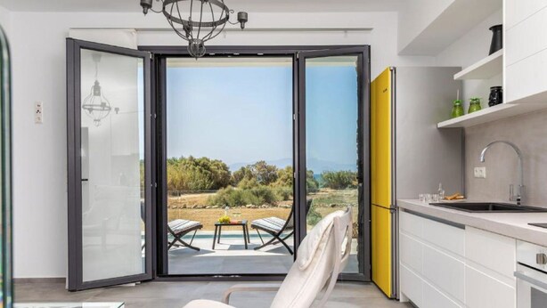 Una cocina moderna con vistas al exterior, un comedor con mesa y sillas, y un armario amarillo.