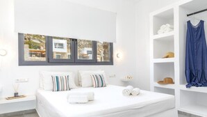 Un dormitorio moderno con una cama grande, un armario empotrado y vistas a un edificio por la ventana.