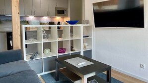 Un salon moderne avec un canapé gris, une table basse et un téléviseur fixé au mur.