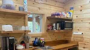 Une cuisine en bois équipée d’une machine à café, d’un four à micro-ondes, d’un évier et de placards.