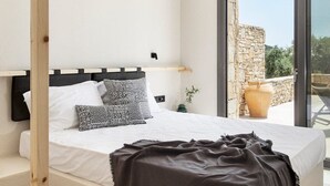 Une chambre à coucher avec un lit, une table de chevet, une lampe, une fenêtre et une vue sur l’extérieur.