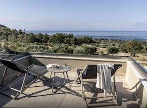 Une terrasse sur le toit offrant une vue sur la mer, avec une table et deux fauteuils de relaxation.