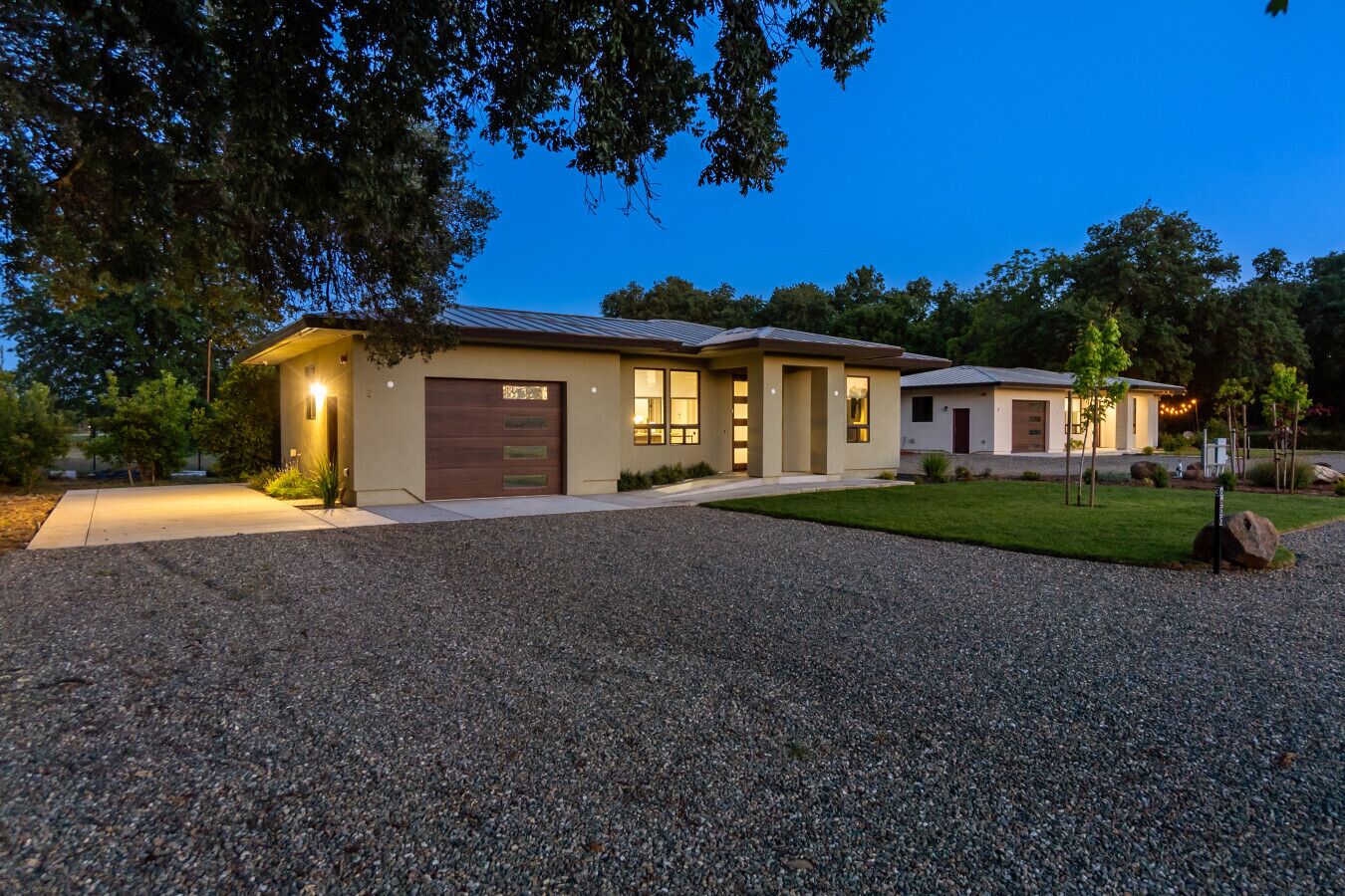 A modern two-story house with a gravel driveway, a garage, and a well-maintained lawn.