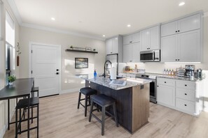 Una cocina moderna con una isla central, muebles blancos y un microondas.