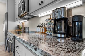 A kitchen with a granite countertop, stainless steel appliances, and a coffee maker.