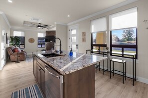 A modern kitchen with a central island, stainless steel appliances, and large windows offering views.