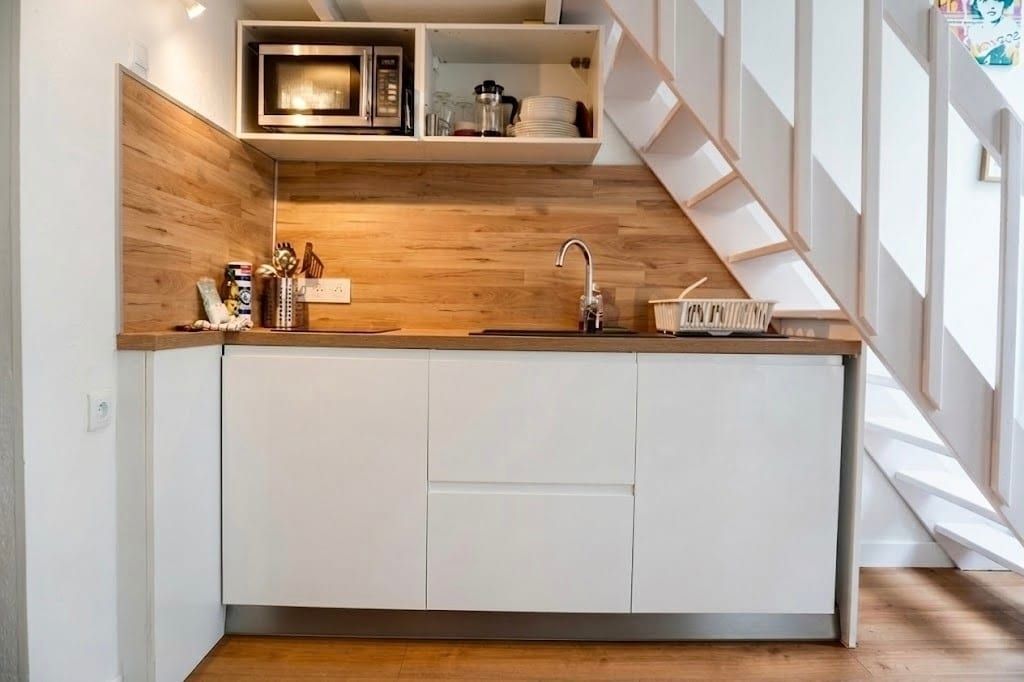 Een moderne keuken met witte kasten, een houten aanrechtblad en een ingebouwde magnetron.