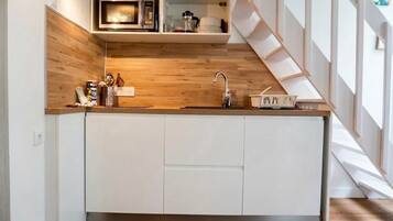 Een moderne keuken met witte kasten, een houten aanrechtblad en een ingebouwde magnetron.