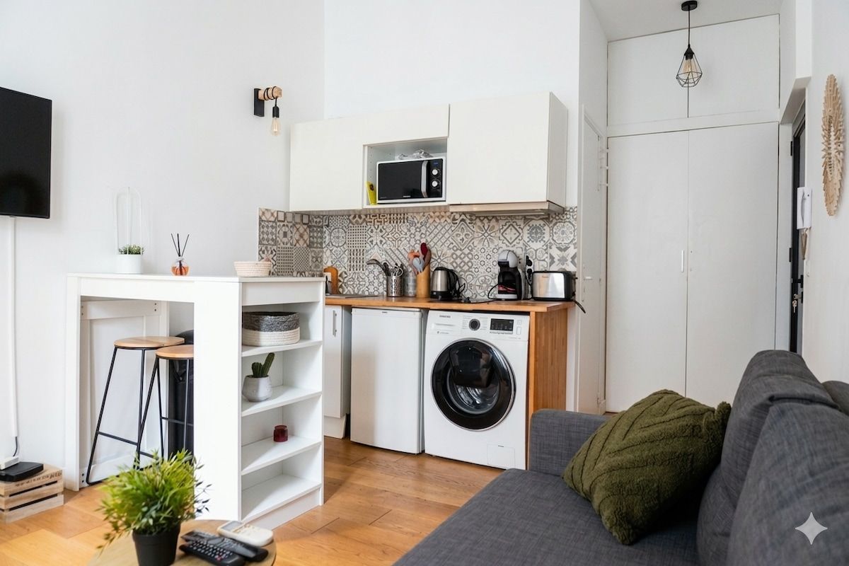 Een knus woongedeelte met een kitchenette, een wasmachine, een magnetron, een bank en een televisie.