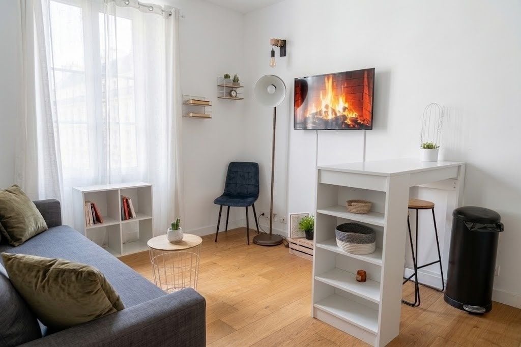 A modern living room with a grey sofa, a blue chair, a white shelving unit, and a floor lamp.