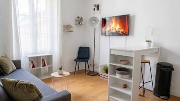 A modern living room with a grey sofa, a blue chair, a white shelving unit, and a floor lamp.