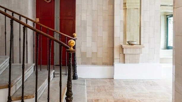 Eine Treppe mit einer roten Tür am oberen Ende, einem Marmorboden und einer Wand mit einer eingebauten Ablagefläche.
