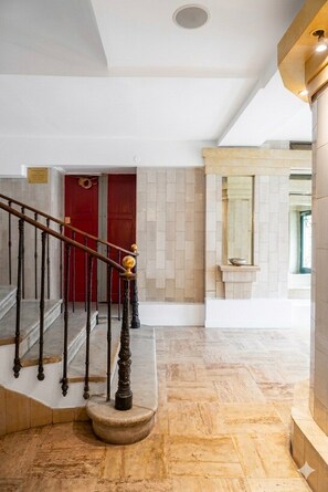 A staircase with a red door at the top, a marble floor, and a wall with a built-in shelf. - La Palmeraie (Nice)