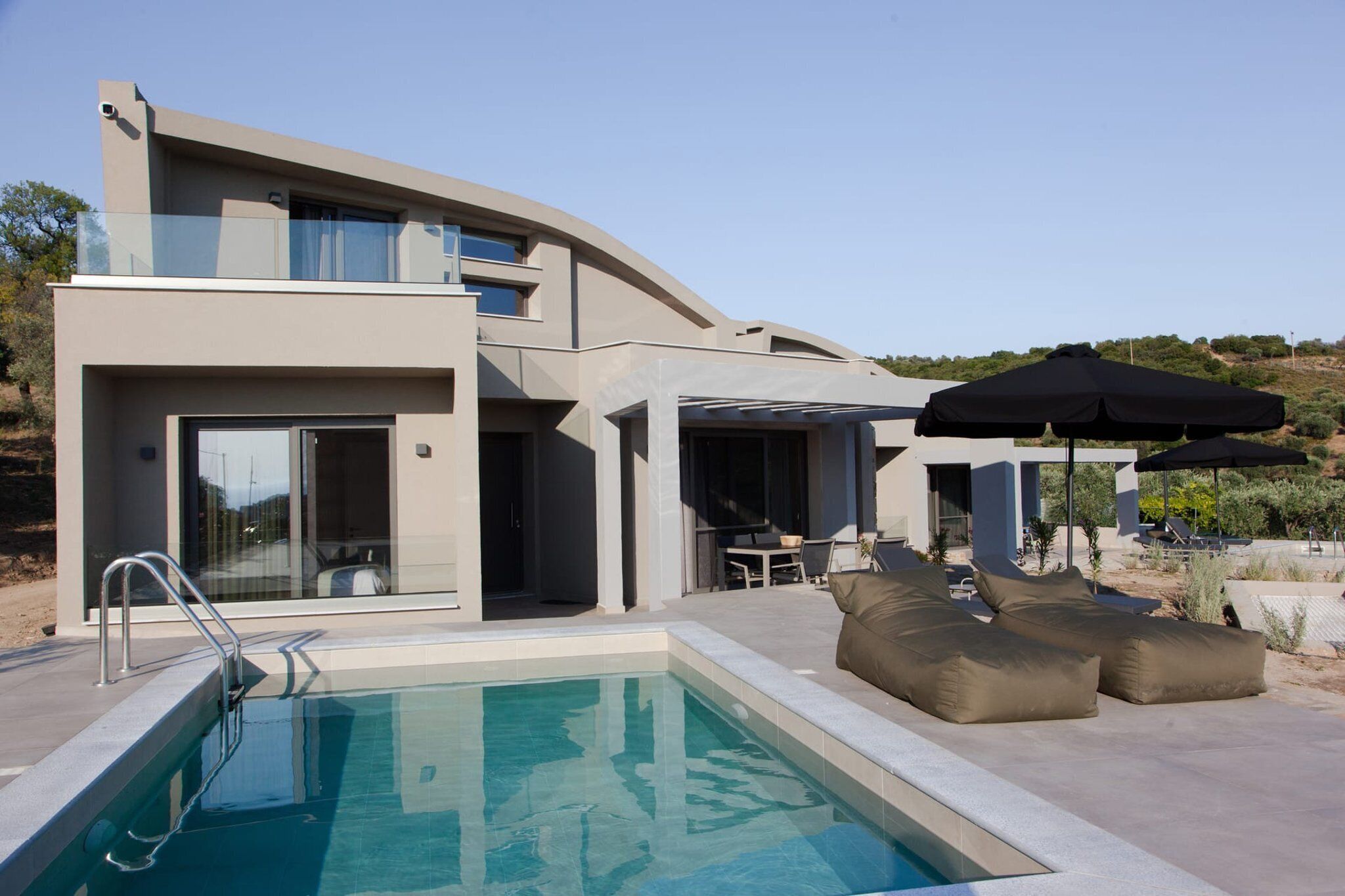 Une maison moderne dotée d’une piscine, d’un espace salon extérieur et d’un patio couvert.