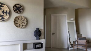 Una habitación con una consola blanca, un florero oscuro y tres tapices tejidos. Una puerta da a otra habitación con una silla y una pequeña mesa.