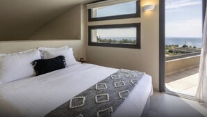 Un dormitorio con una cama grande, dos ventanas y vista al mar.