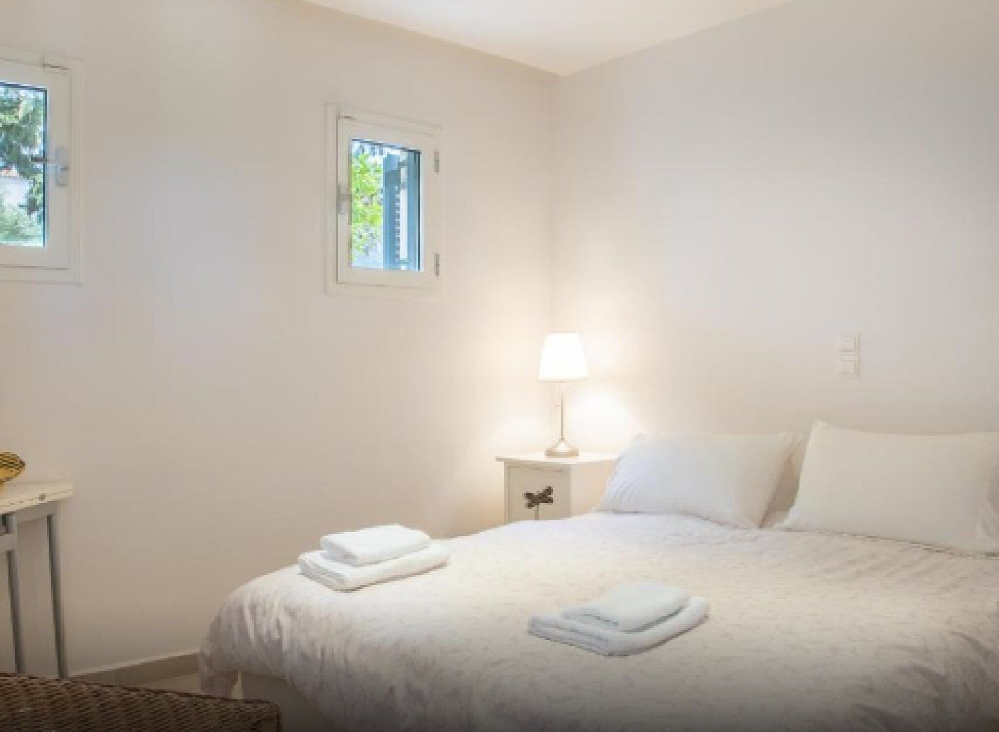 Une chambre à coucher avec un lit, une table de chevet avec une lampe et une fenêtre.