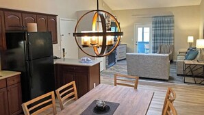 A modern kitchen with dark wooden cabinets, a black refrigerator, and a dining area with a wooden table and chairs. - Cozy 1-bedroom resort with AC in welcoming Massanutten with waterPark access (Massanutten)